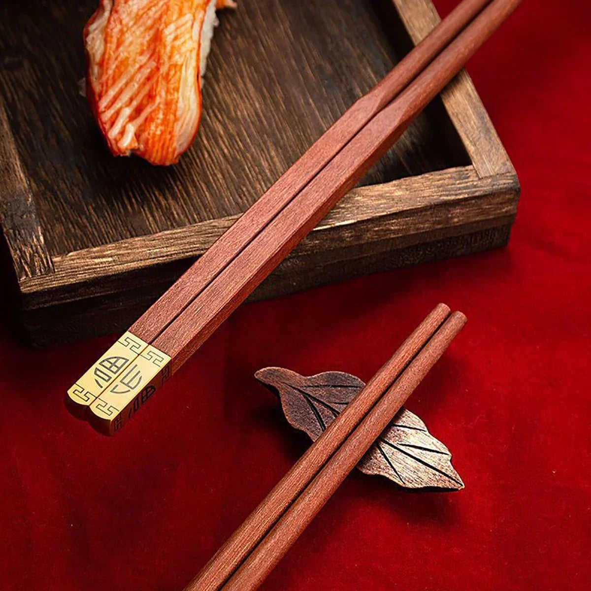 Close-up of red wood chopsticks with square tips and gold inlay