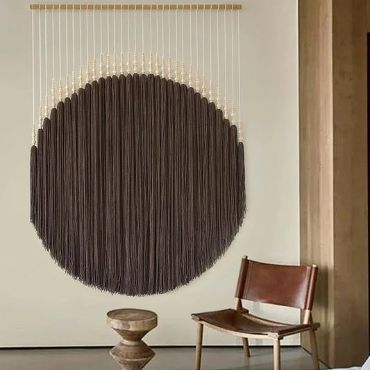 Round brown macramé wall hanging with beaded design on neutral wall